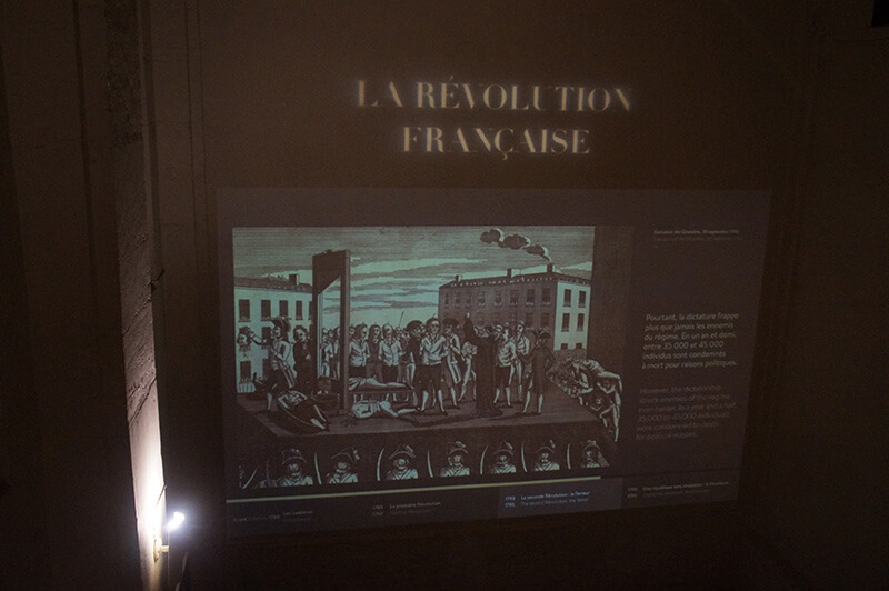 牆上投影幕，播放著法國大格命的過程，法國大革命重要舞台之一，就是巴黎古監獄。