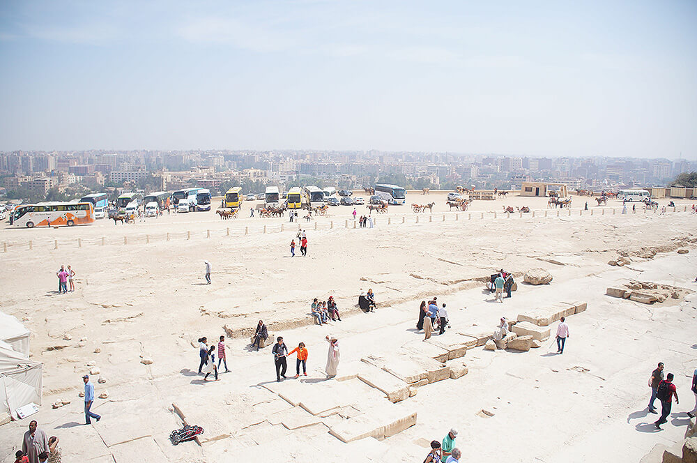 站在金字塔上，眺望開羅市區與遊覽車之視角。