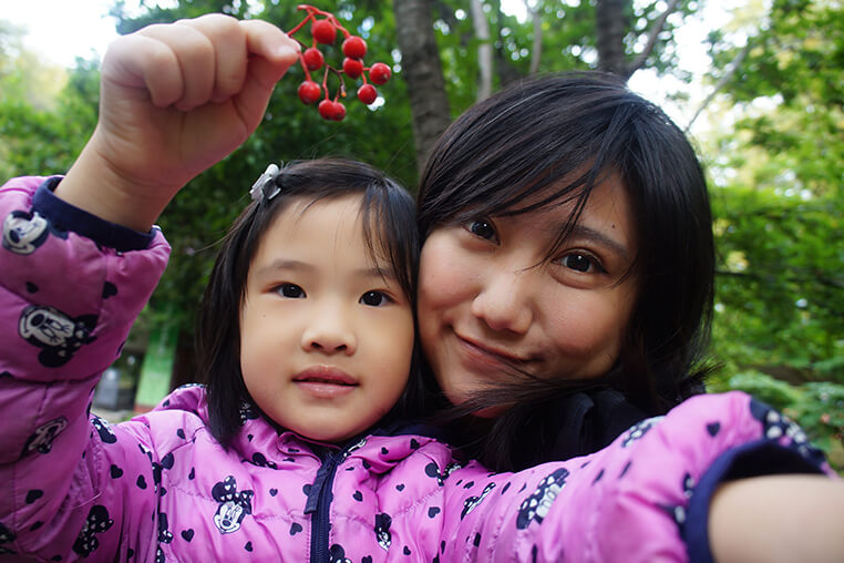 小女孩撿到心愛的紅色果實，興奮分享。